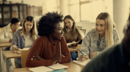 Photo of two students at a table talking in what appears to be a pair-share activity