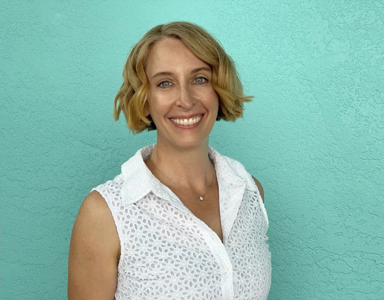 Image of Dr. Jen Golbeck. She is standing in front of a teal wall, smiling.
