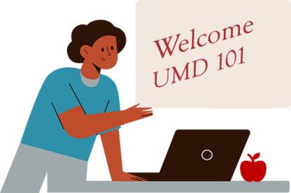 Instructor with brown skin and a turquoise shirt stands in front of a board that reads, Welcome UMD 101