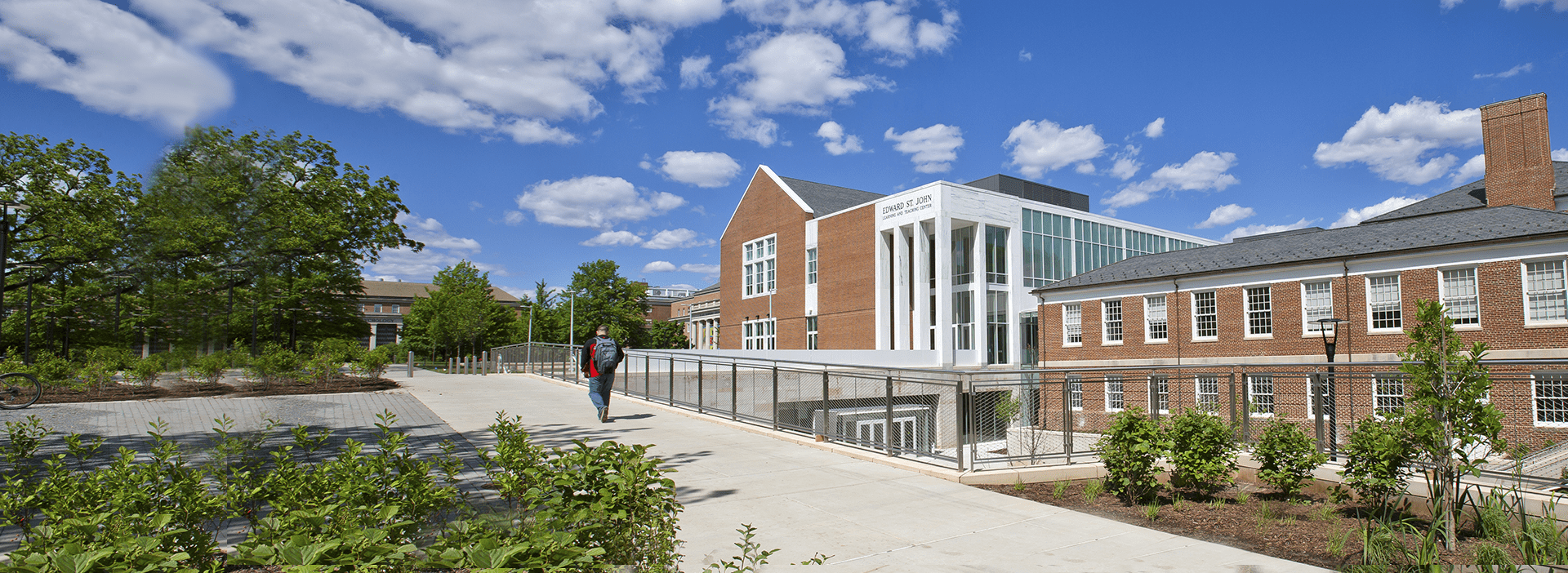 Wide banner of Edward St. John building and the greenery around it on a bright and sunny day.