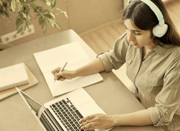 One instructor sitting at a computer with headphones on taking notes